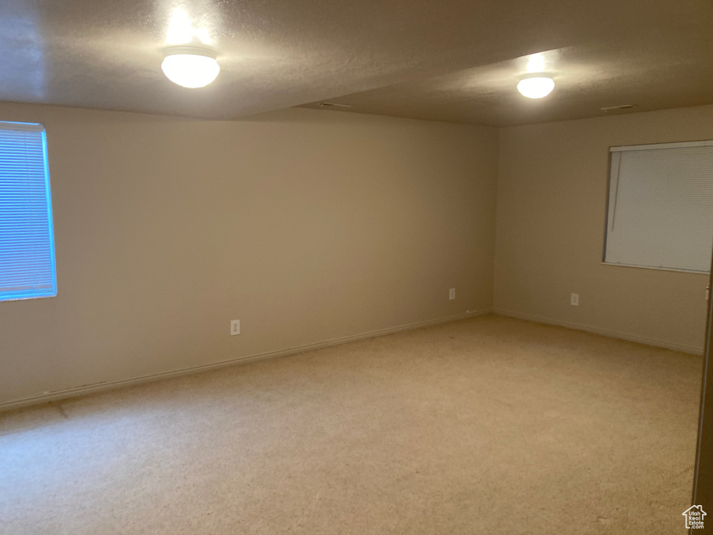 Spare room featuring baseboards and light carpet