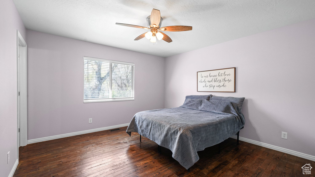 Bedroom with hardwood / wood-style flooring, baseboards, visible vents, and ceiling fan