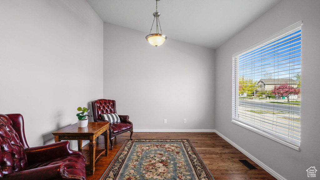 Living area with dark wood-style flooring, visible vents, baseboards, and lofted ceiling