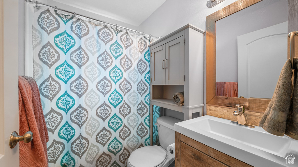 Bathroom with curtained shower, vanity, and toilet
