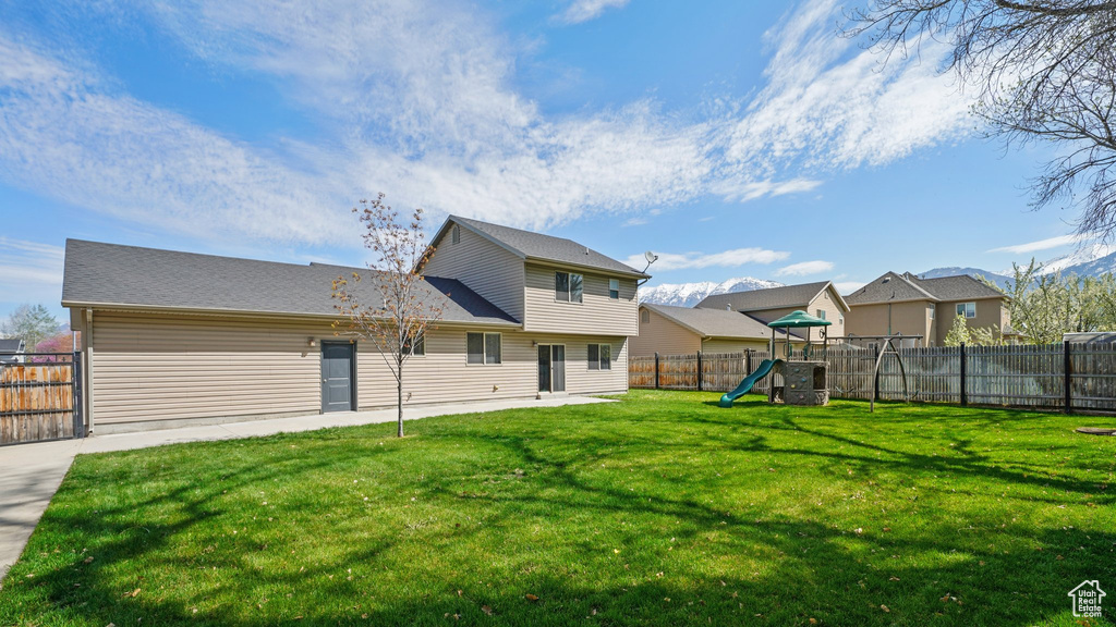 Back of house with a yard, a fenced backyard, and a playground