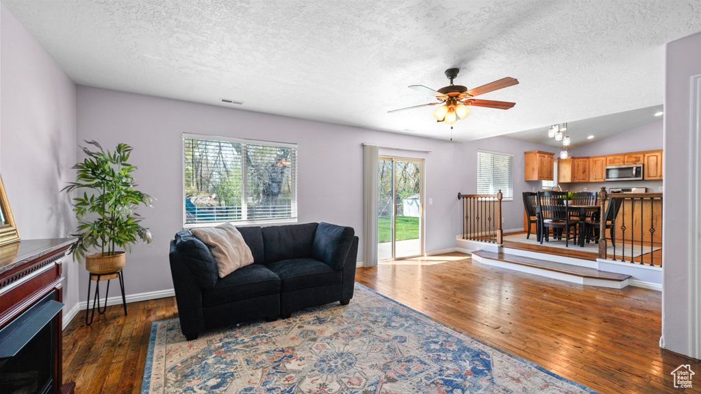 Living room featuring visible vents, hardwood / wood-style flooring, a ceiling fan, and a textured ceiling