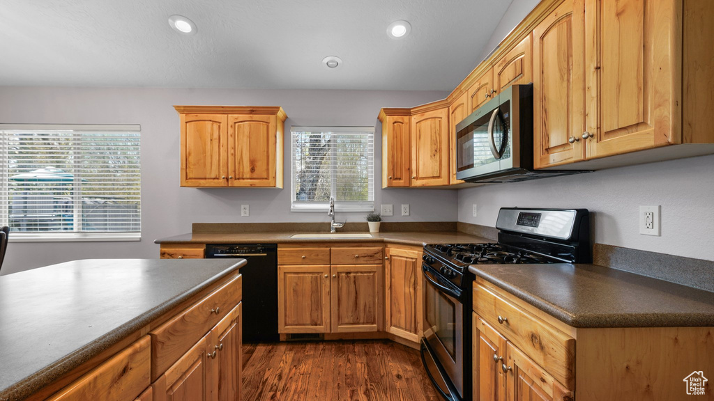 Kitchen with a sink, dark countertops, dark wood-style floors, and stainless steel appliances
