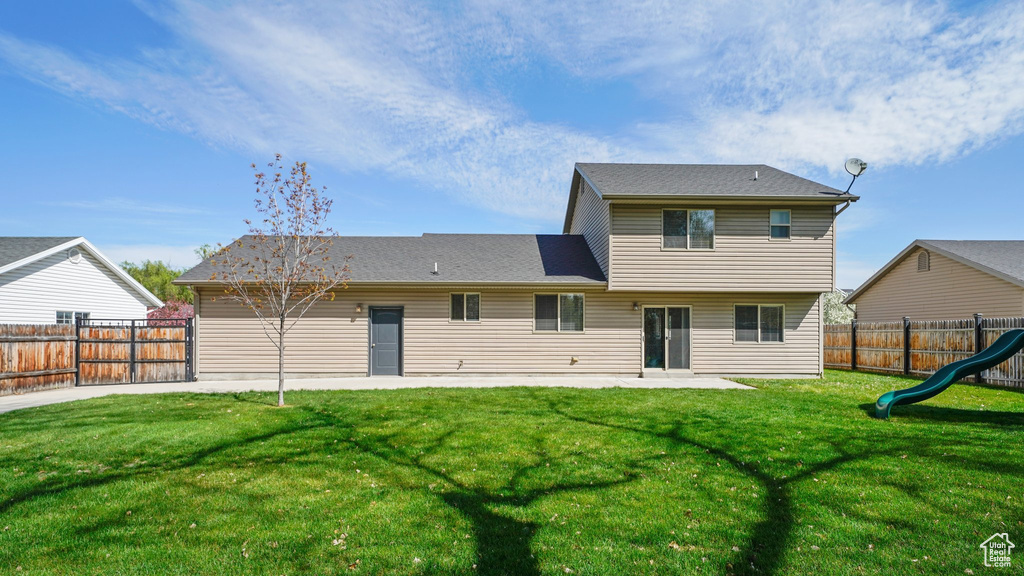 Rear view of property featuring a yard, a fenced backyard, and a patio