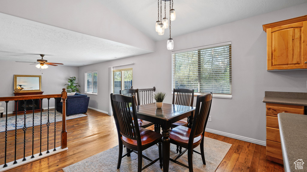 Dining room with lofted ceiling, light wood-type flooring, baseboards, and ceiling fan