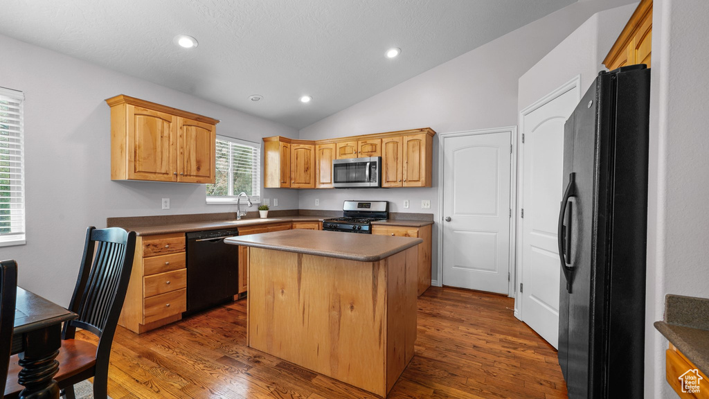 Kitchen with dark wood finished floors, a sink, black appliances, and lofted ceiling