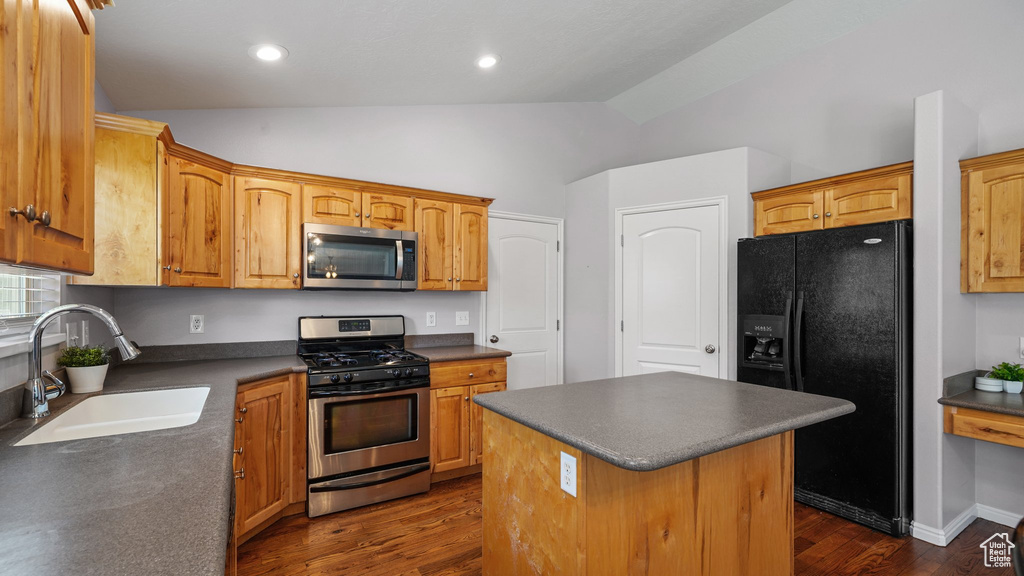 Kitchen with appliances with stainless steel finishes, dark countertops, a kitchen island, lofted ceiling, and a sink