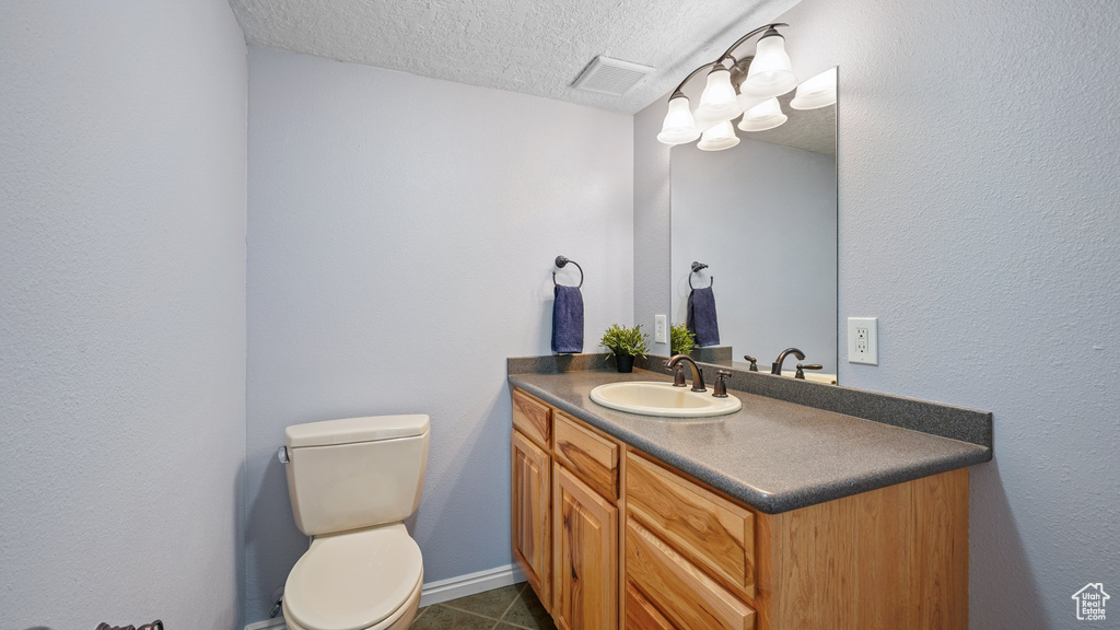Bathroom featuring visible vents, toilet, a textured ceiling, vanity, and tile patterned floors