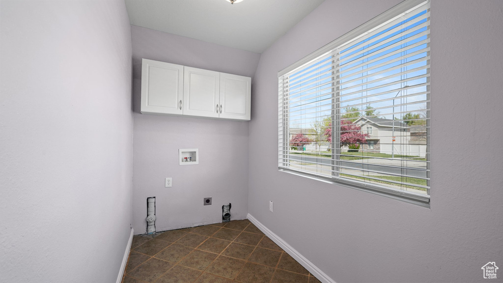 Laundry room with cabinet space, dark tile patterned flooring, hookup for an electric dryer, and washer hookup