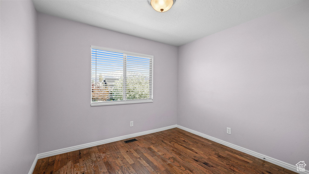 Empty room with visible vents, baseboards, and dark wood-style floors