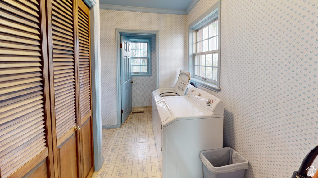 Washroom with wallpapered walls, crown molding, washer and clothes dryer, laundry area, and light floors