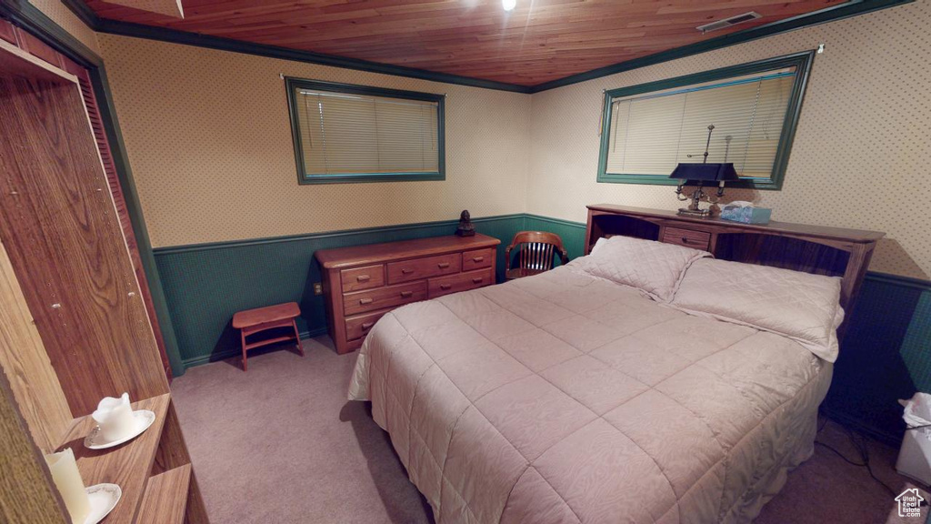 Bedroom with wallpapered walls, carpet, visible vents, and a wainscoted wall