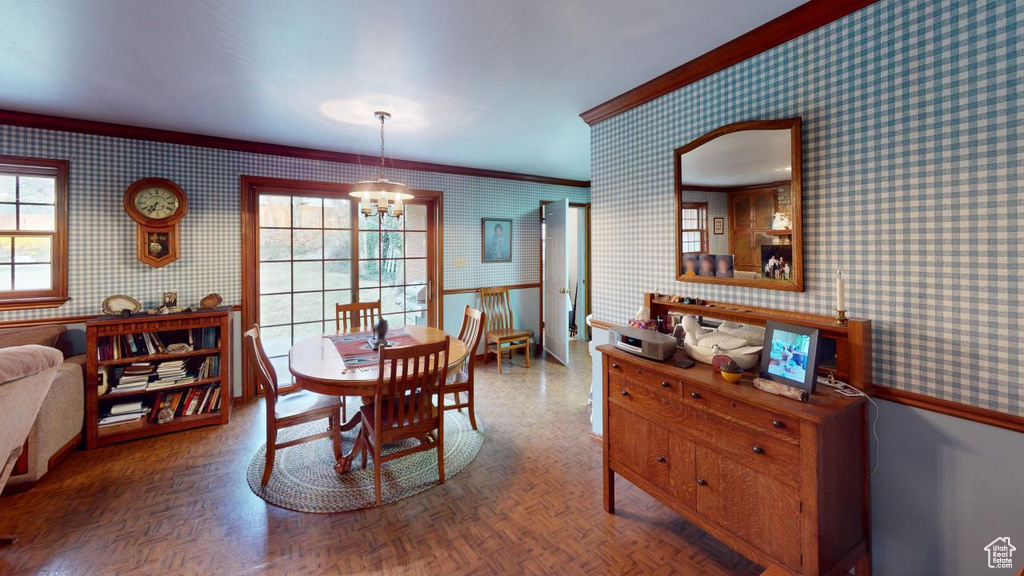 Dining room featuring crown molding, an inviting chandelier, and wallpapered walls