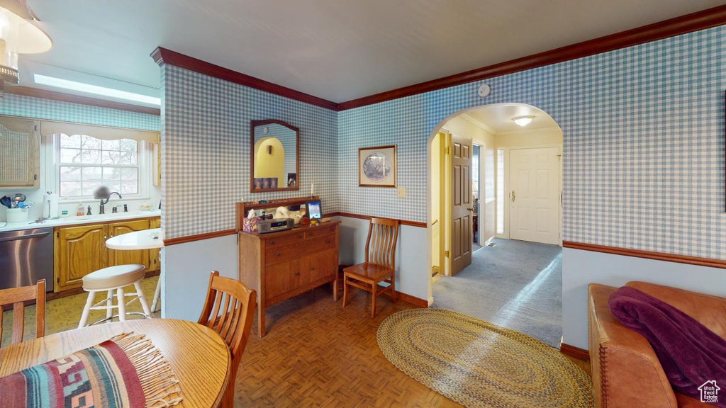 Dining room with arched walkways, wallpapered walls, baseboards, and ornamental molding