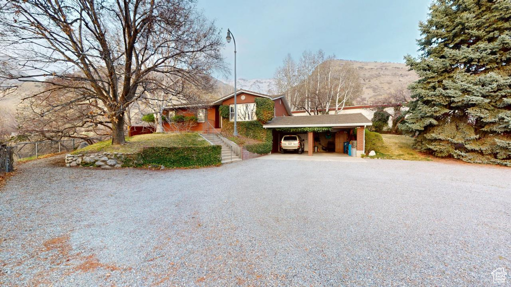 Ranch-style house with a mountain view, a carport, driveway, and fence