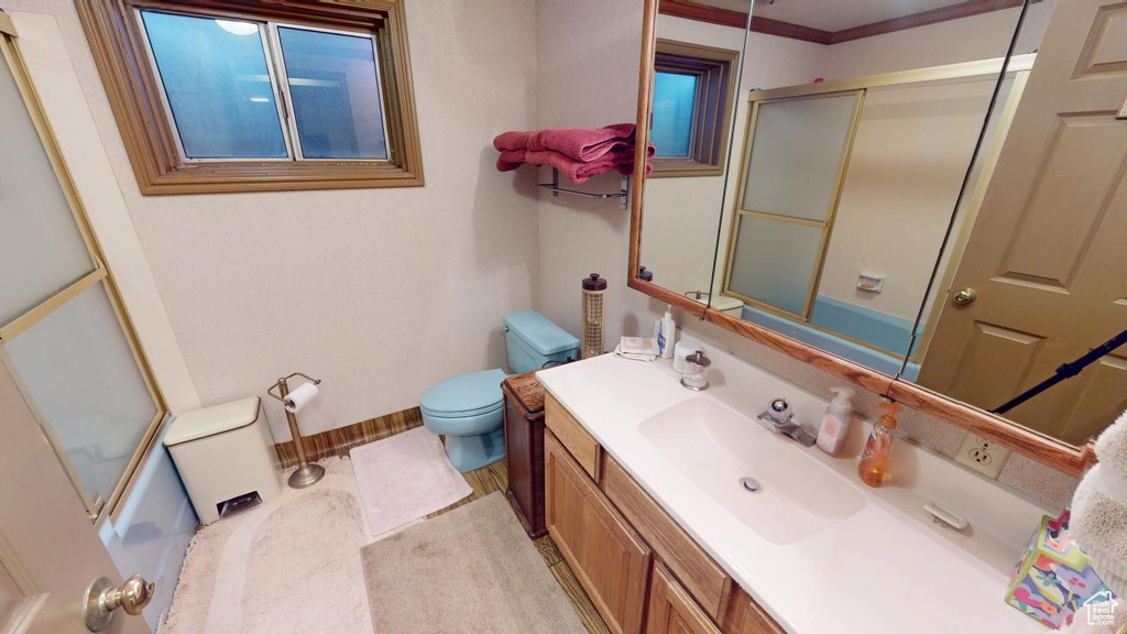 Bathroom featuring toilet, vanity, and a shower with door