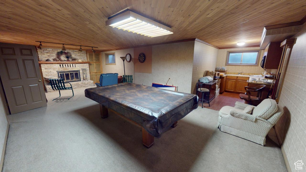 Recreation room with pool table, rail lighting, carpet, wooden ceiling, and a brick fireplace
