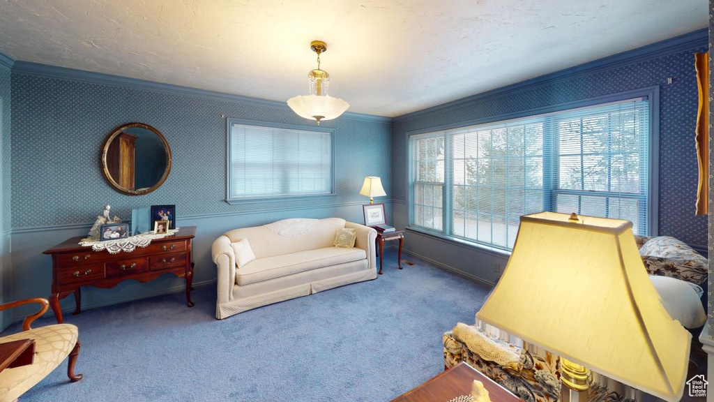 Living room with carpet flooring, wallpapered walls, and crown molding