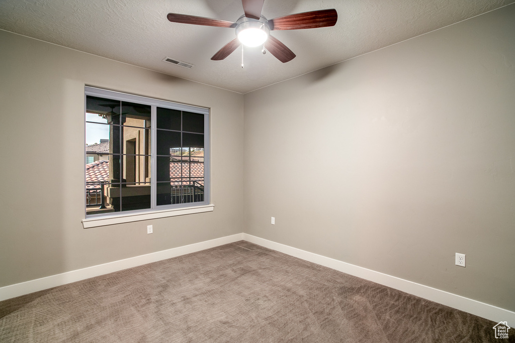 Carpeted spare room featuring a ceiling fan, a textured ceiling, baseboards, and visible vents