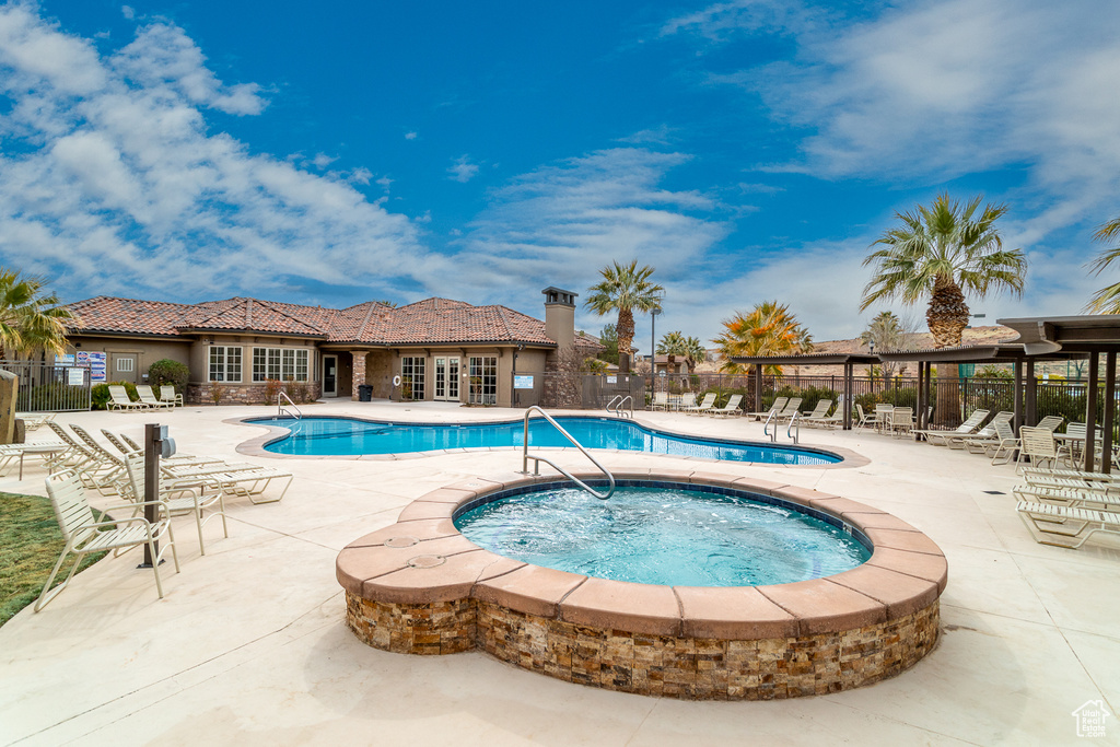 Pool featuring fence, a community hot tub, and a patio area