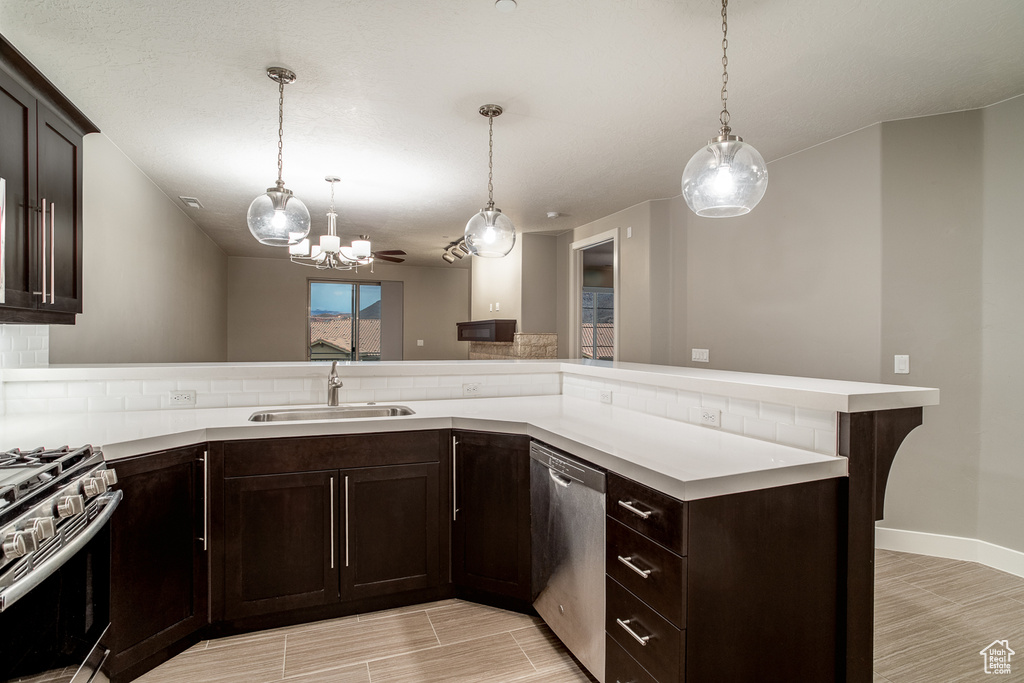 Kitchen with decorative backsplash, light countertops, stainless steel appliances, a sink, and an inviting chandelier
