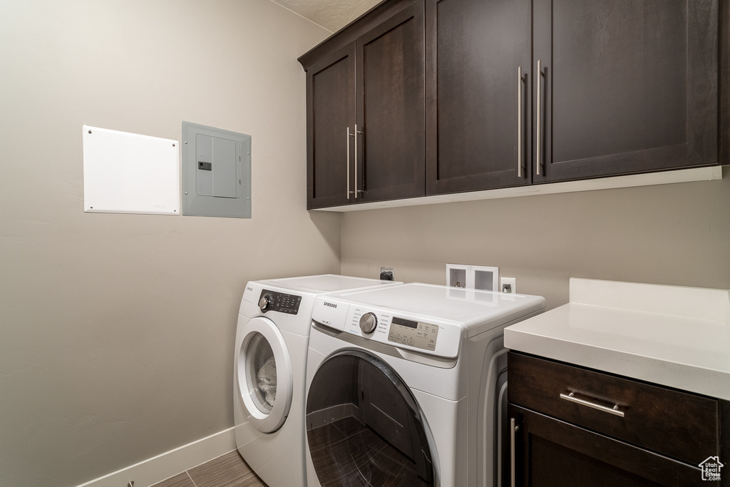 Laundry room with cabinet space, baseboards, separate washer and dryer, and electric panel