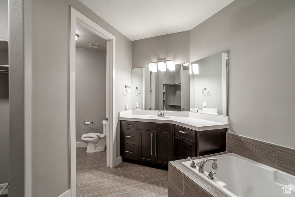 Bathroom featuring toilet, vanity, and a bath