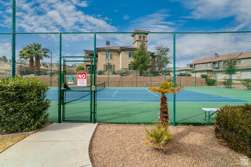 View of tennis court with a gate and fence