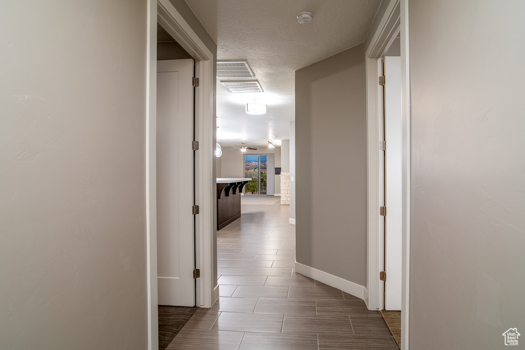 Corridor with baseboards and a textured ceiling