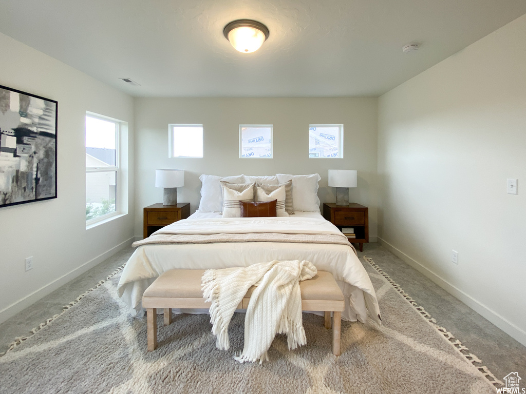 Bedroom with light colored carpet, baseboards, and visible vents