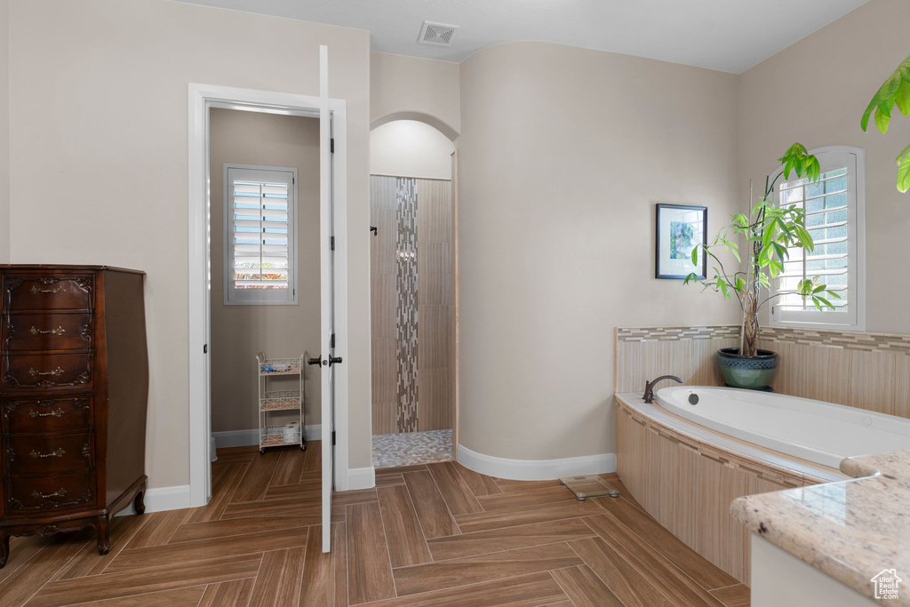 Full bath with visible vents, a tile shower, baseboards, and a garden tub