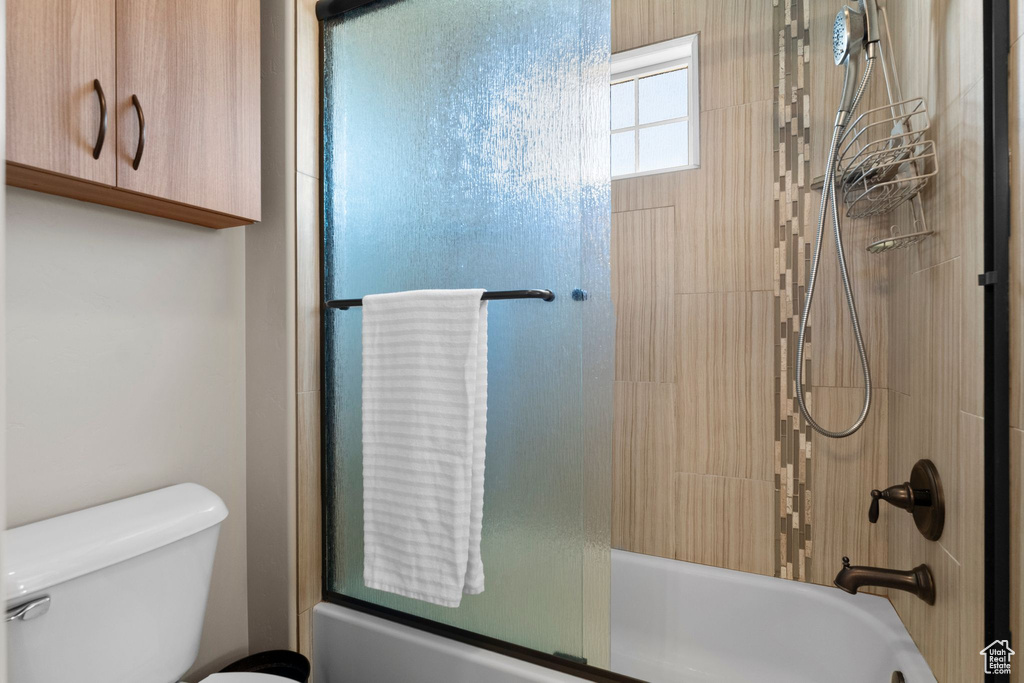 Bathroom with toilet and shower / bath combination with glass door