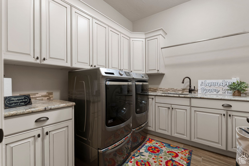 Washroom featuring a sink, cabinet space, separate washer and dryer, and light wood-style floors