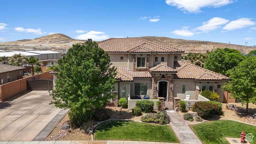 Mediterranean / spanish home with stucco siding, a gate, a mountain view, fence, and a tiled roof