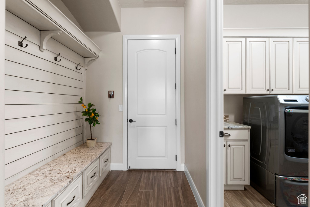 Clothes washing area with cabinet space, washer / clothes dryer, baseboards, and dark wood-style flooring