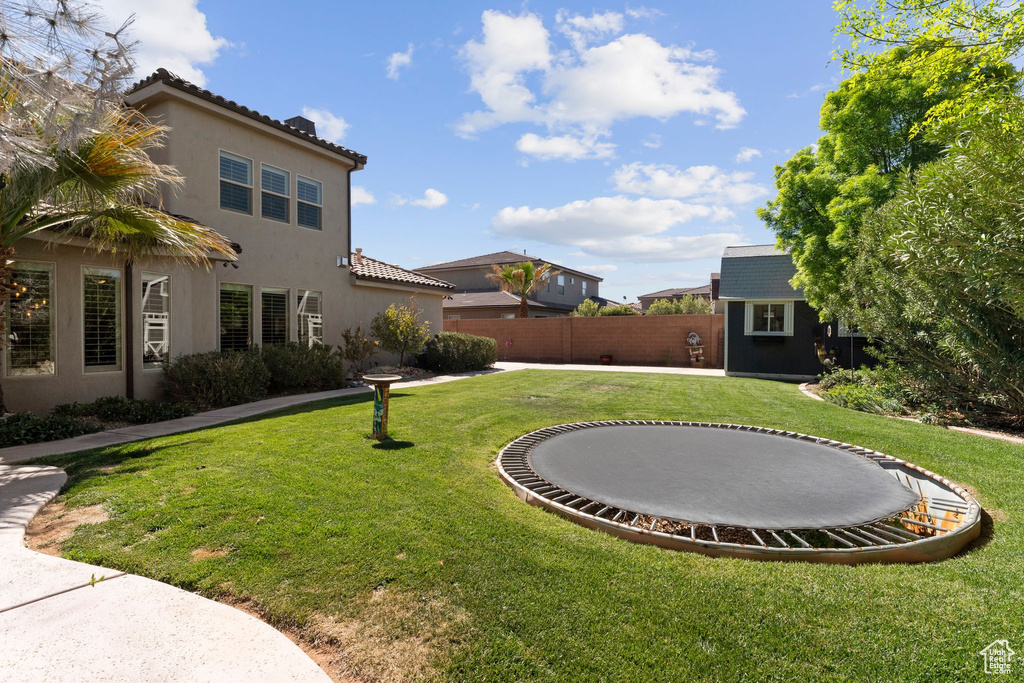 View of yard featuring an outbuilding, fence, and a trampoline