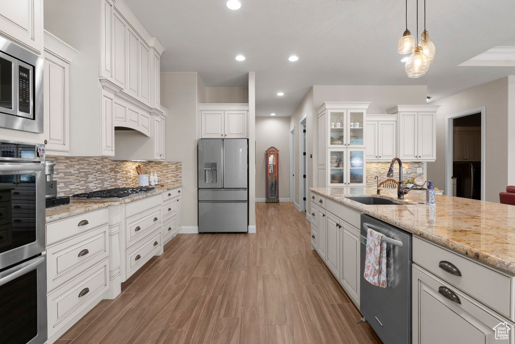 Kitchen featuring white cabinets, a sink, stainless steel appliances, baseboards, and backsplash
