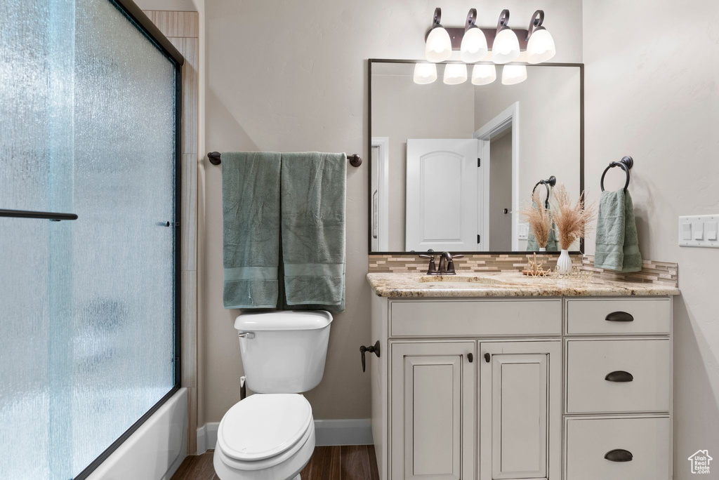Bathroom with vanity, baseboards, toilet, decorative backsplash, and wood finished floors
