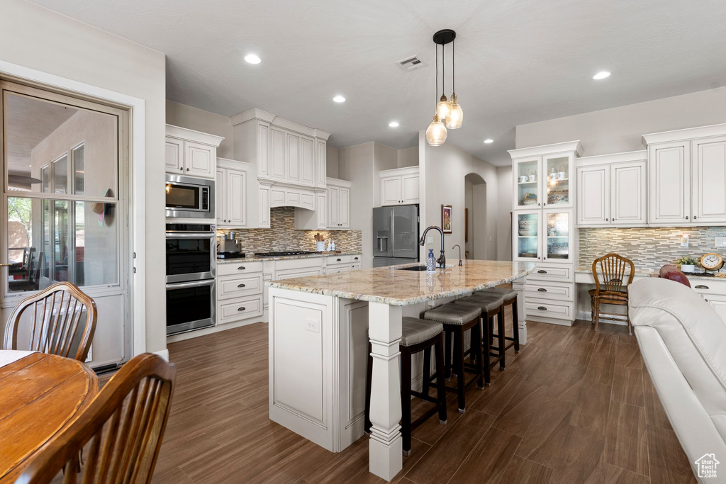 Kitchen featuring a sink, dark wood finished floors, decorative backsplash, and stainless steel appliances