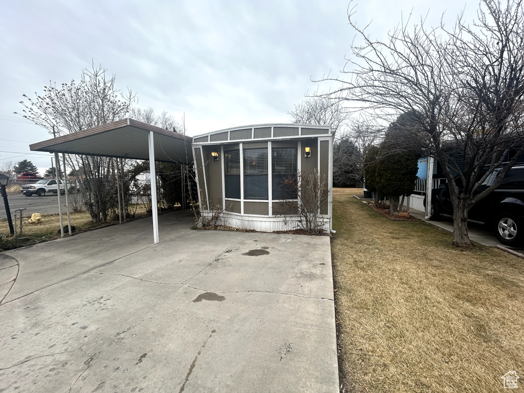Back of house featuring a yard, a carport, a sunroom, and driveway
