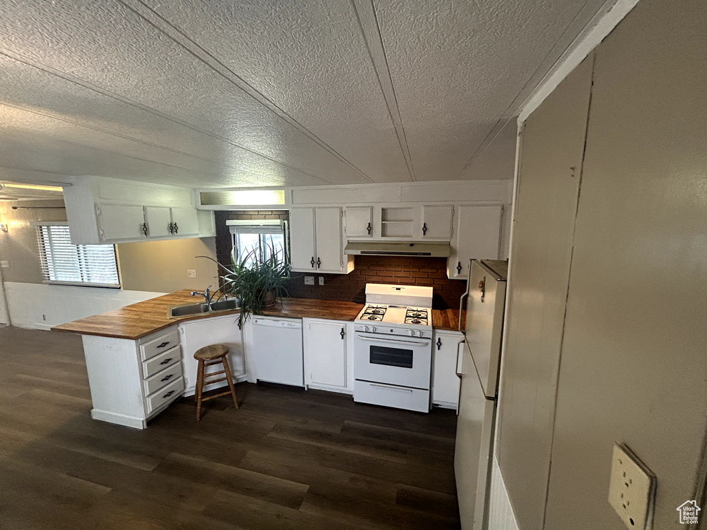 Kitchen featuring range hood, white appliances, butcher block countertops, and dark wood-style floors