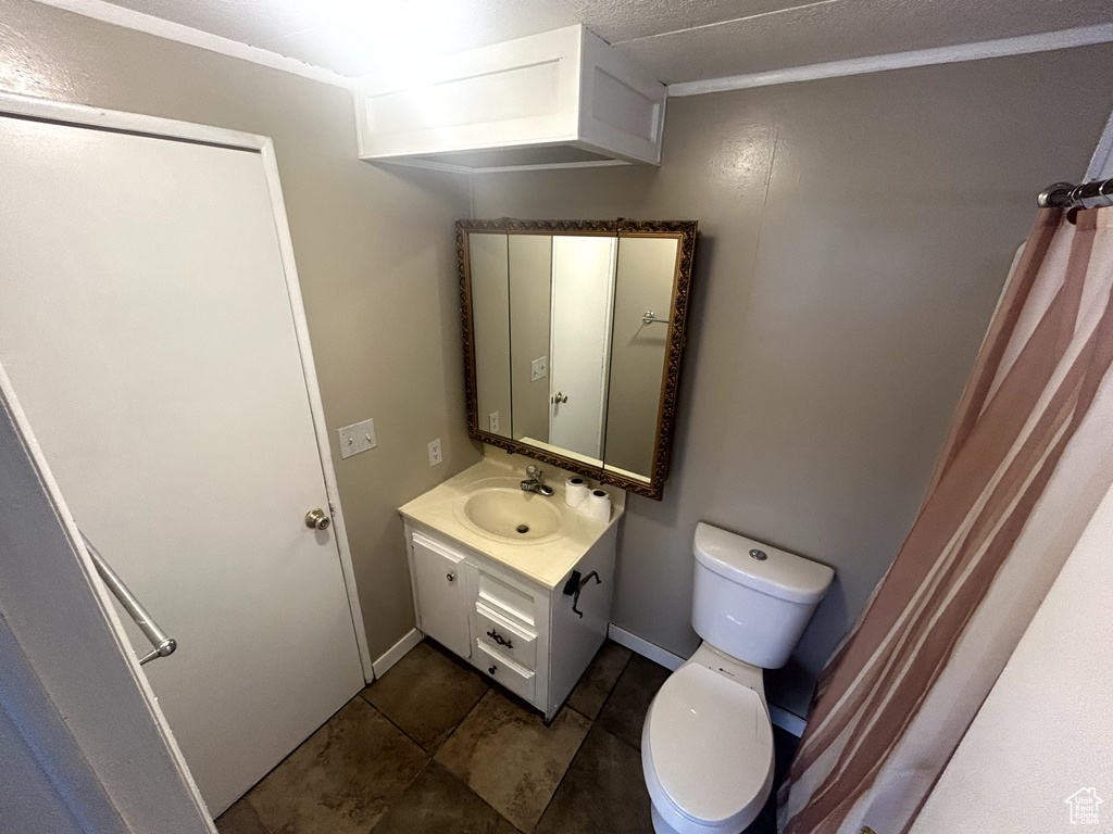 Bathroom with tile patterned floors, vanity, baseboards, and toilet