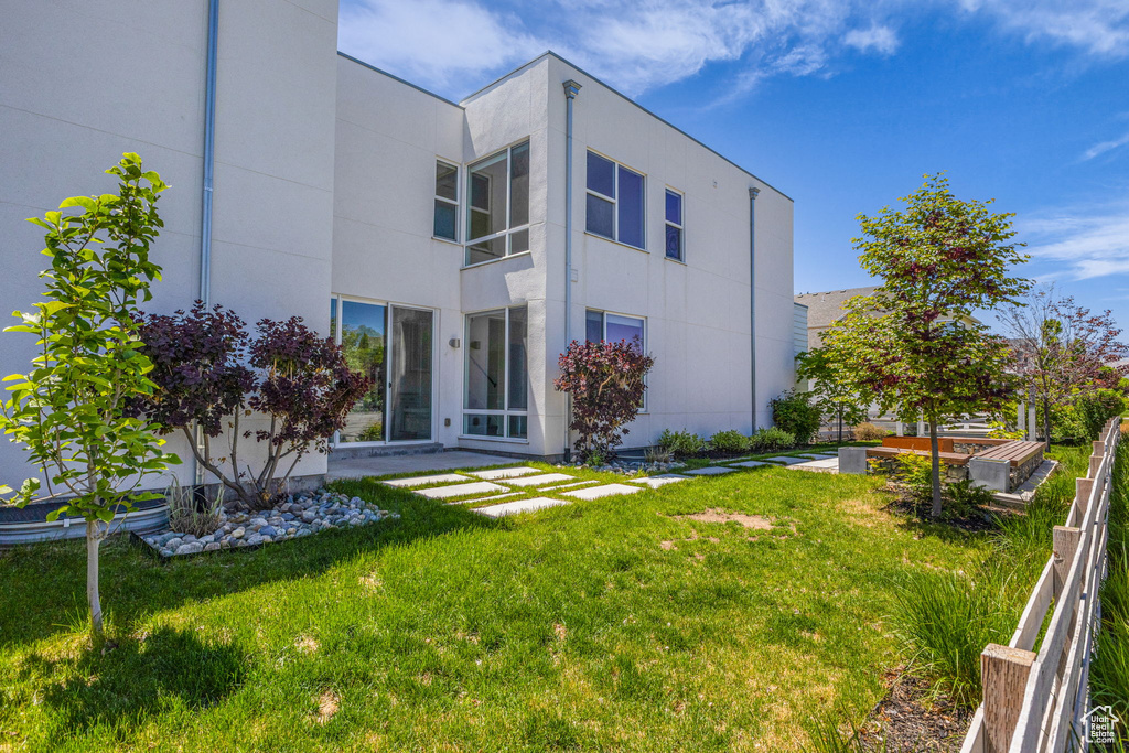 Rear view of property with a yard and stucco siding
