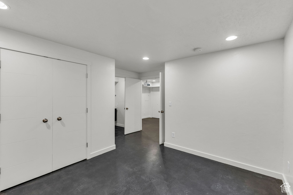 Unfurnished bedroom featuring recessed lighting, concrete flooring, baseboards, and a closet