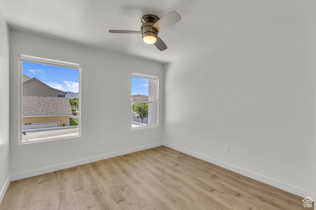 Empty room featuring light wood-style flooring, baseboards, and a ceiling fan