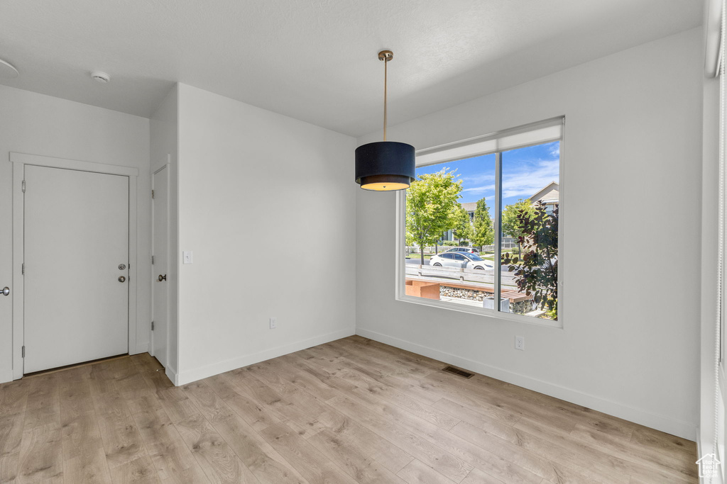 Unfurnished dining area featuring light wood finished floors and baseboards