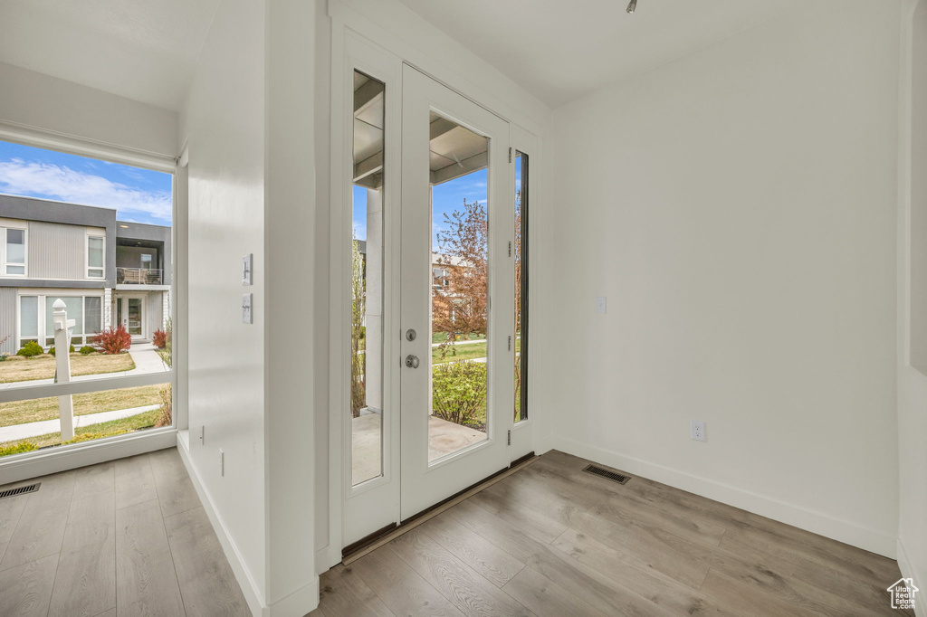 Doorway to outside with healthy amount of natural light, wood finished floors, and baseboards