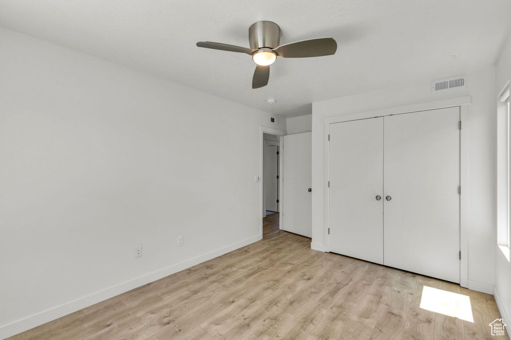 Unfurnished bedroom featuring light wood-style floors, baseboards, a closet, and ceiling fan