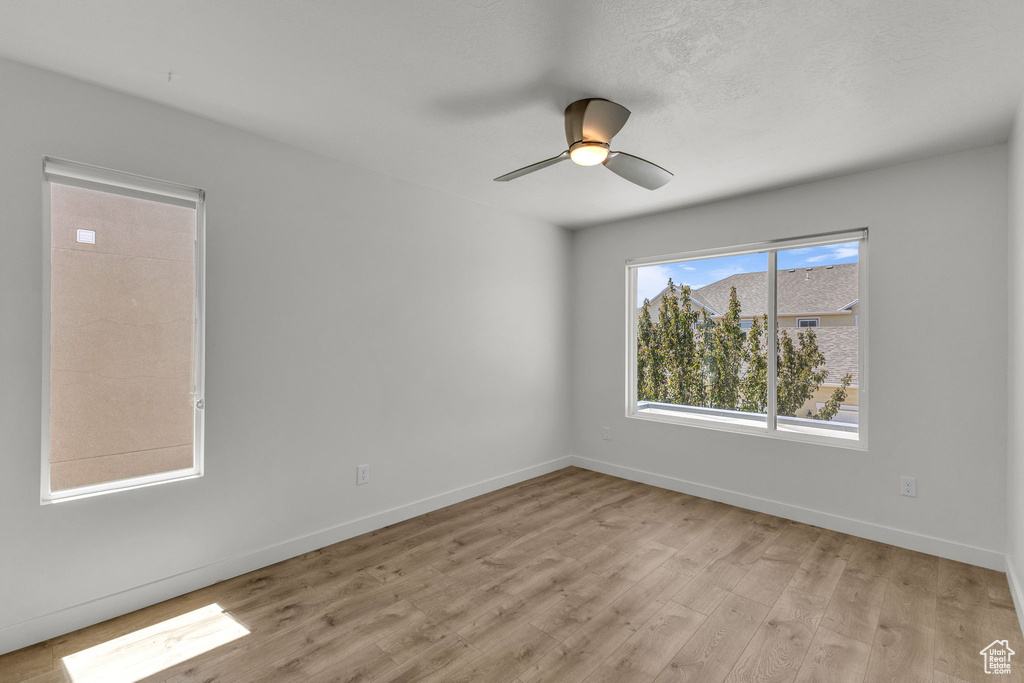 Empty room featuring light wood-style flooring, baseboards, and ceiling fan