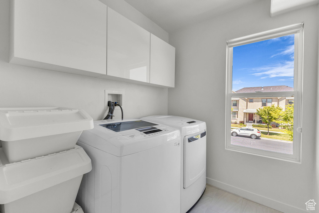 Laundry room with cabinet space, washer and dryer, baseboards, and light marble finish floors